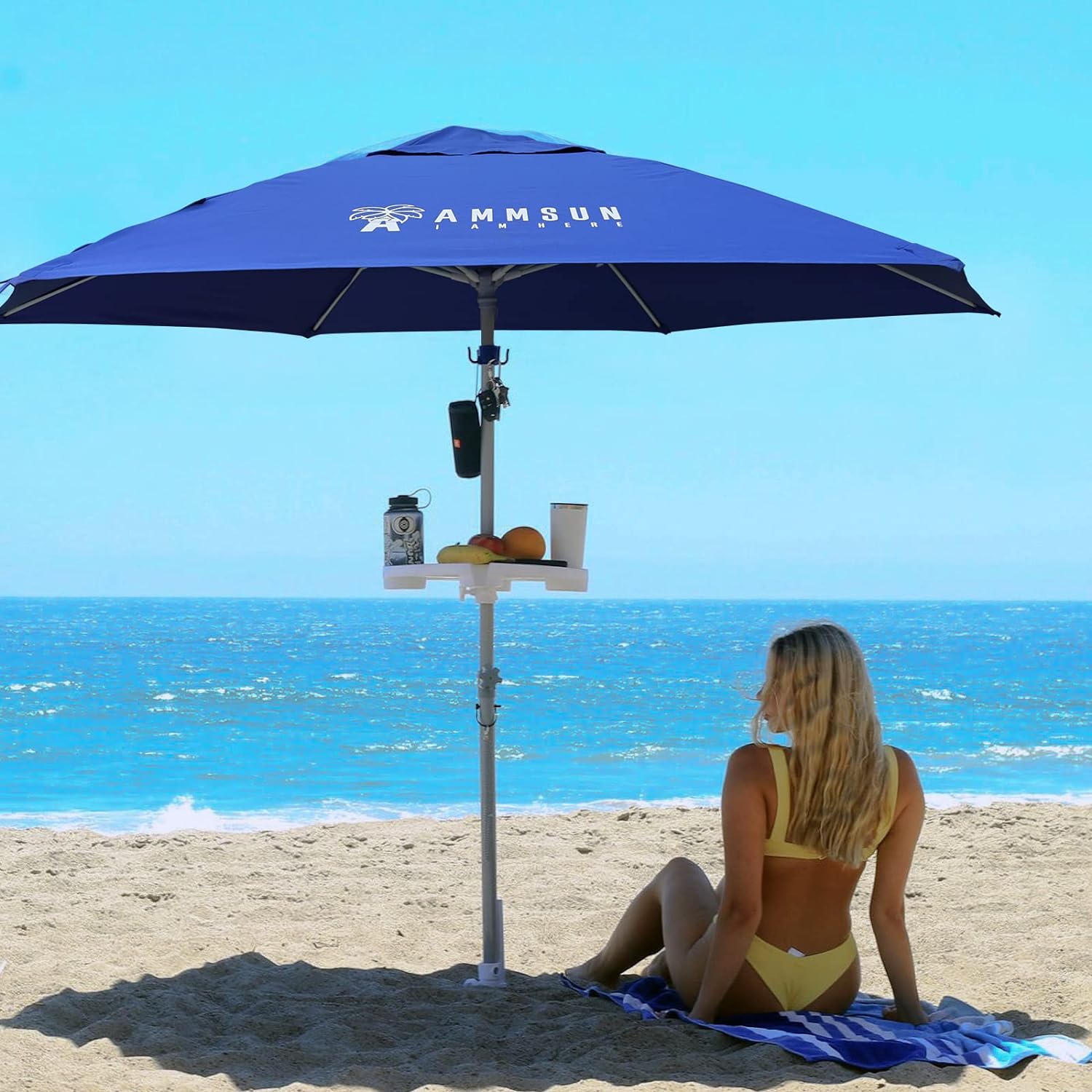 A woman sitting under AMMSUN blue 8ft beach umbrellas for sand heavy duty wind portable