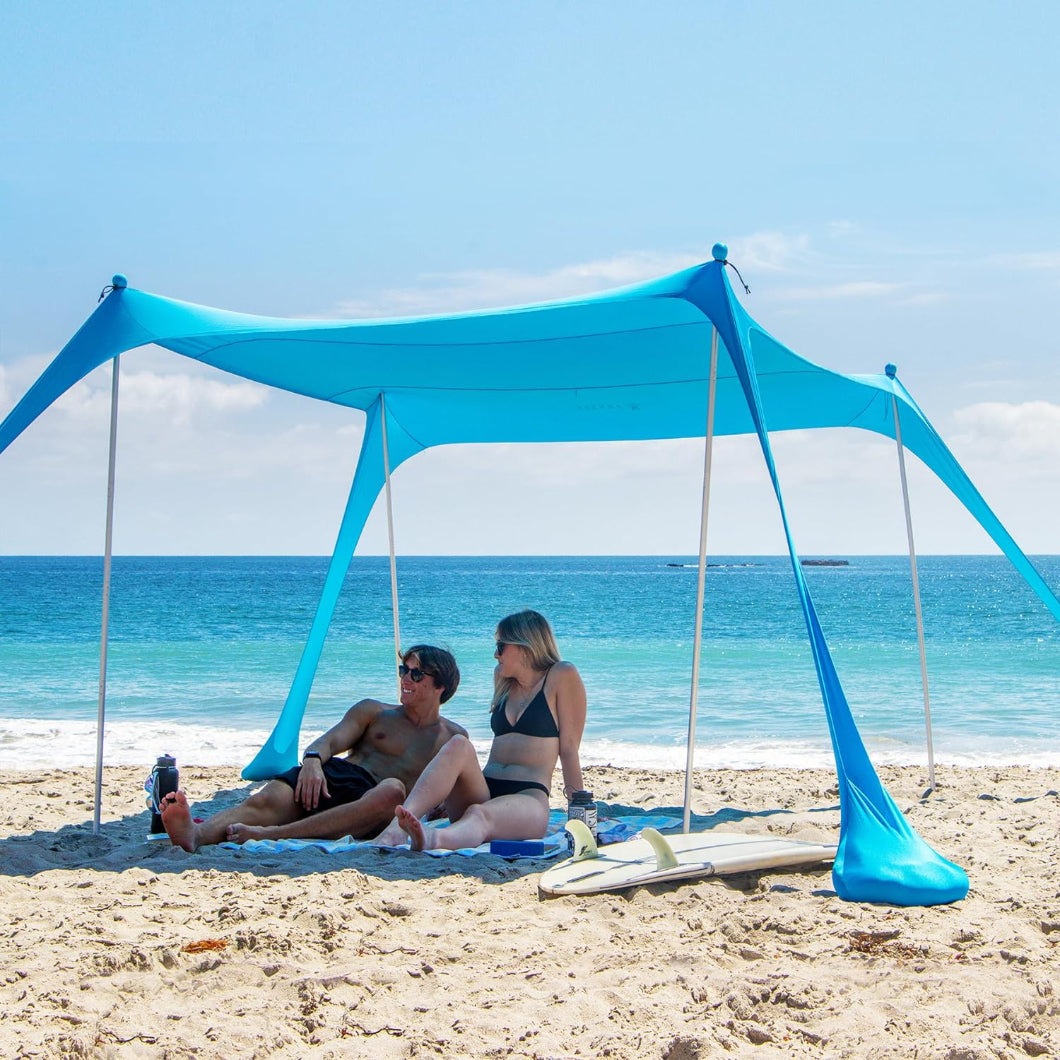 Two individuals seated beneath AMMSUN light blue 9x9ft Portable Lycra Beach Tent on beach