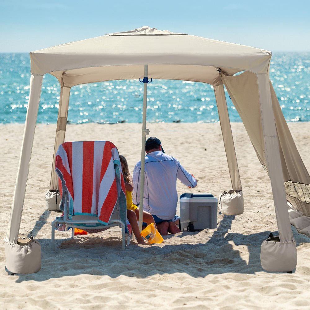 Two people relax under an AMMSUN vintage beige 6.2' × 6.2' beach cabana for sand with privacy sunwall for cabana tent