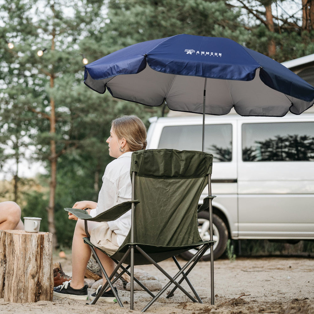 A woman sitting in camp chair with canopy AMMSUN navy blue 52 inches chair umbrella with universal clamp