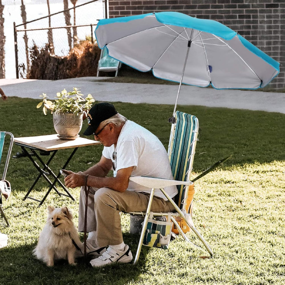 A man seated in a lawn chair with a dog shaded by 43