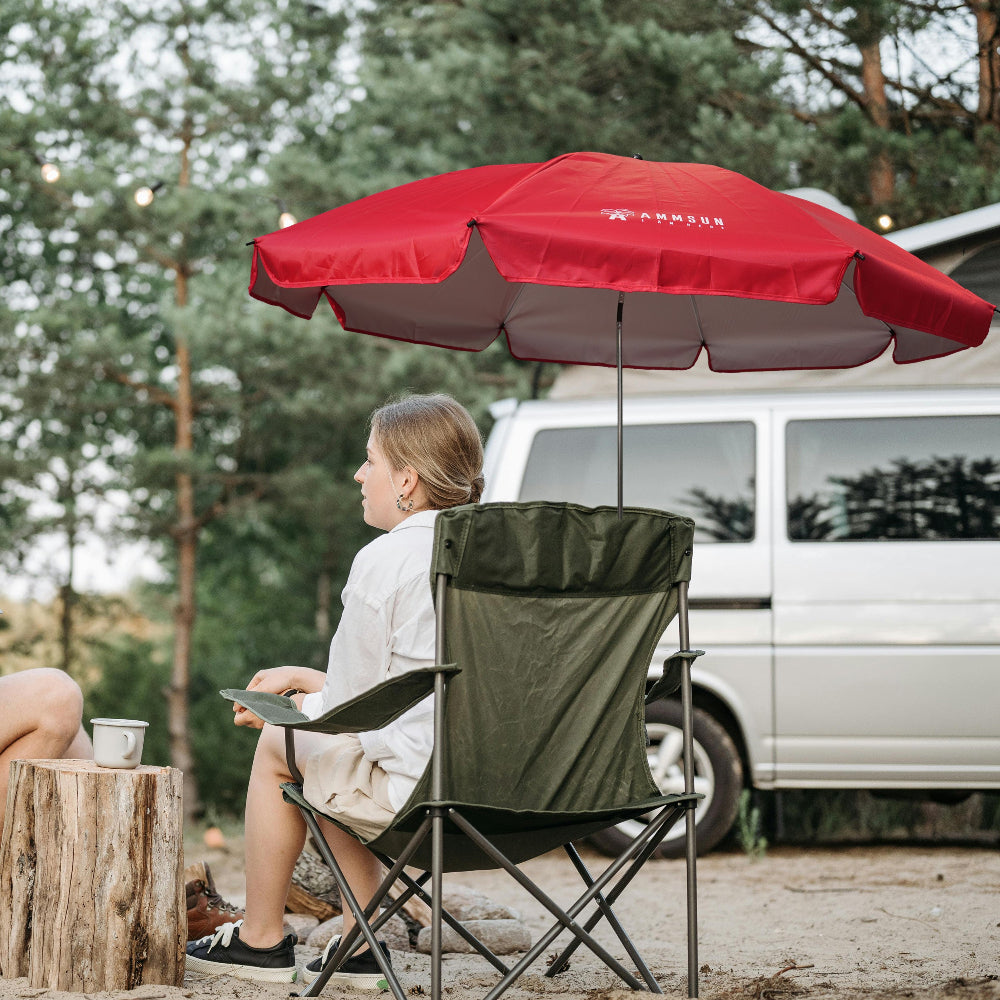 A woman sitting beneath AMMSUN red 52 inches portable umbrella for chair with universal clamp