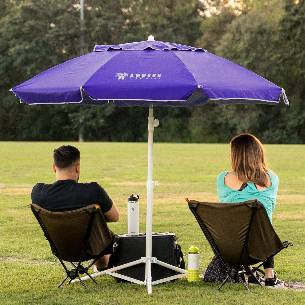 Two people sitting nder AMMSUN 6.5ft purple portable umbrella with stand for sun shade in a lush field