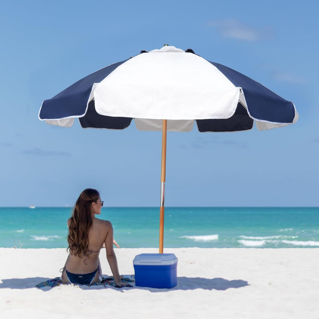 A woman sits under AMMSUN dark blue/white 7.5ft patio umbrella commercial grade beach umbrella on beach