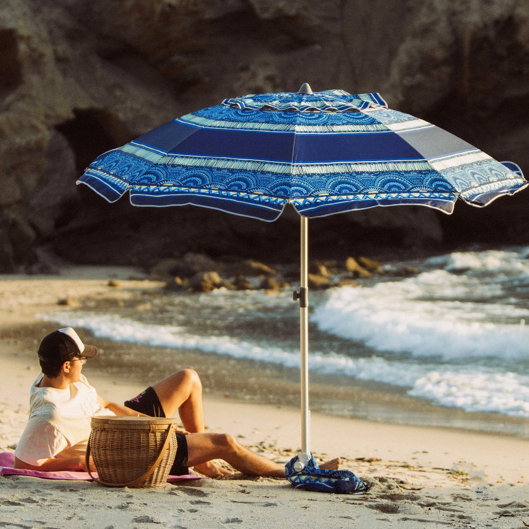  A man enjoys a peaceful moment on the beach, lying beneath AMMSUN 7ft  Revival Blues beach umbrella with sand anchor