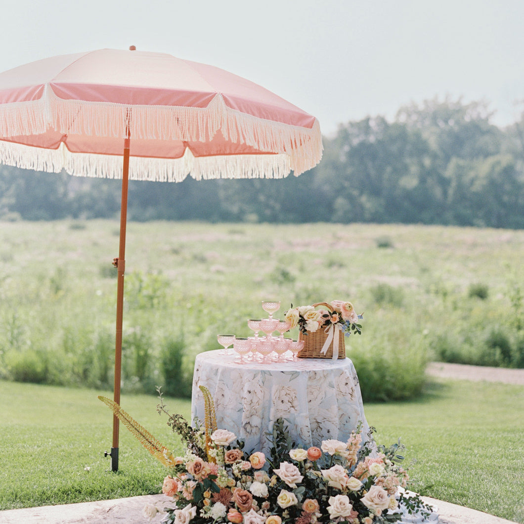 A beautifully set wedding table in pink and white, adorned with an elegant AMMSUN 7ft pink picnic umbrella with fringe