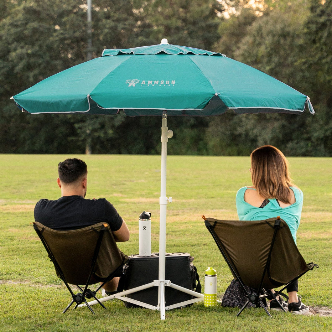 A couple enjoys a peaceful moment under AMMSUN 6.5ft turquoise sun shade umbrella with base in a field