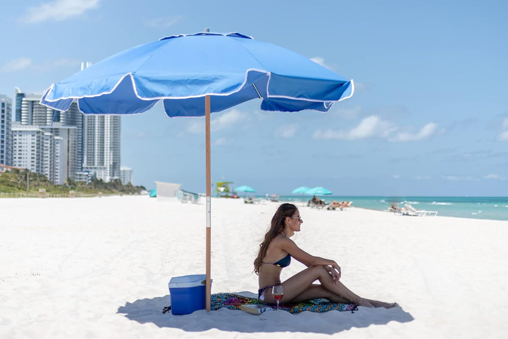 A woman enjoys a serene moment under AMMSUN 7.5ft commercial grade blue beach shade umbrella on beach