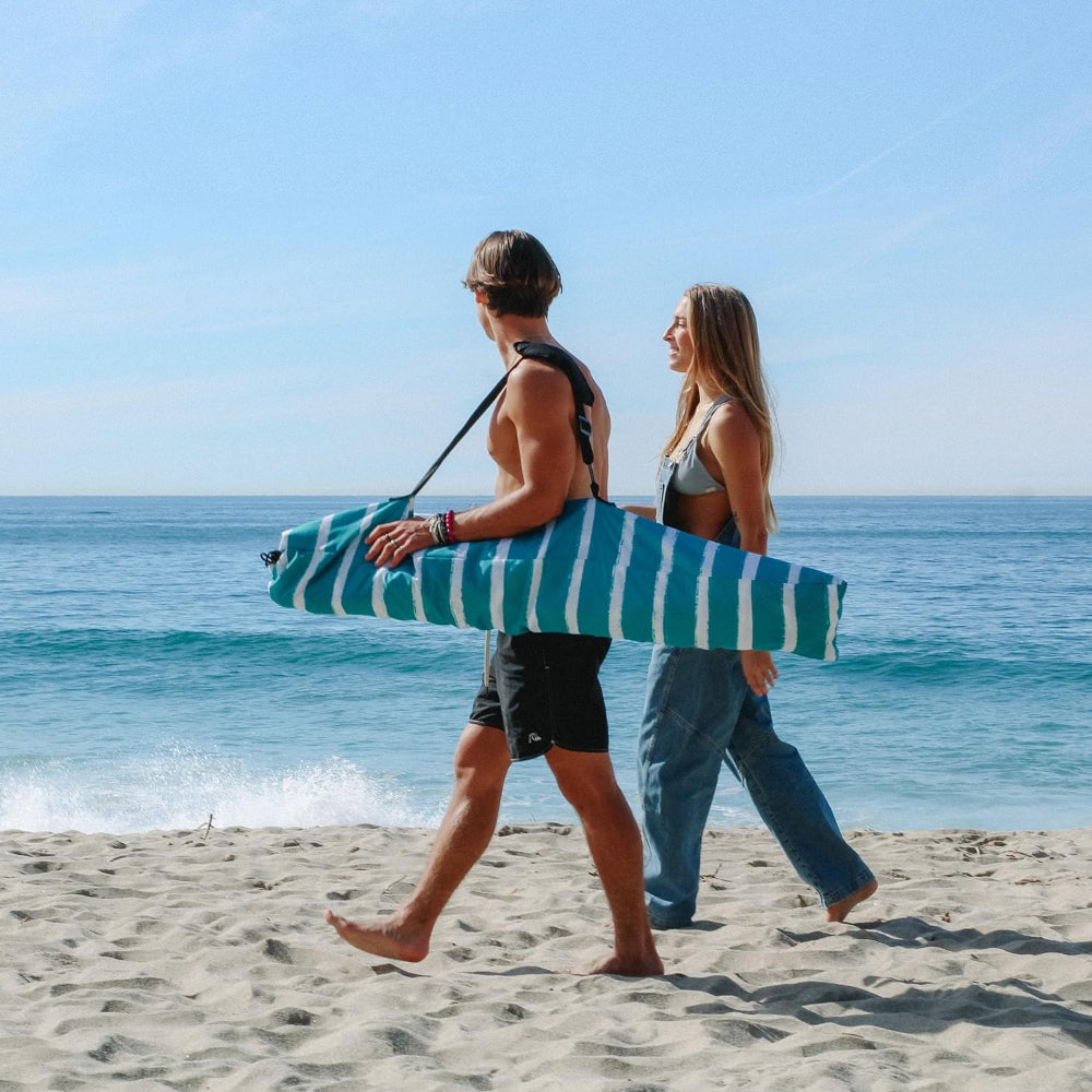 A couple are walking on the beach with a carry bag for AMMSUN 6.2'×6.2' royal turquoise beach shade cabana with privacy sunwall