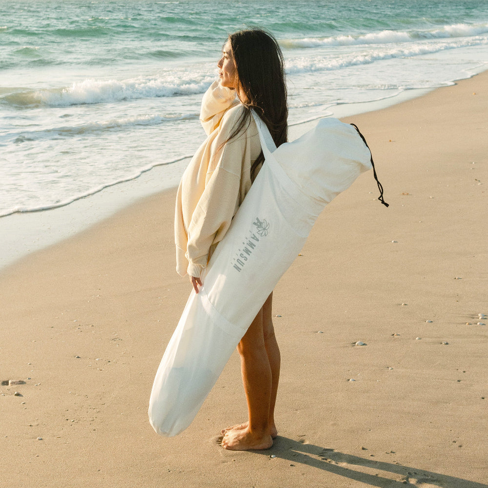 A woman stands on the beach, confidently holding a carry bag for AMMSUN 6'×6' Bobo cabana with Fringe,Elegant white