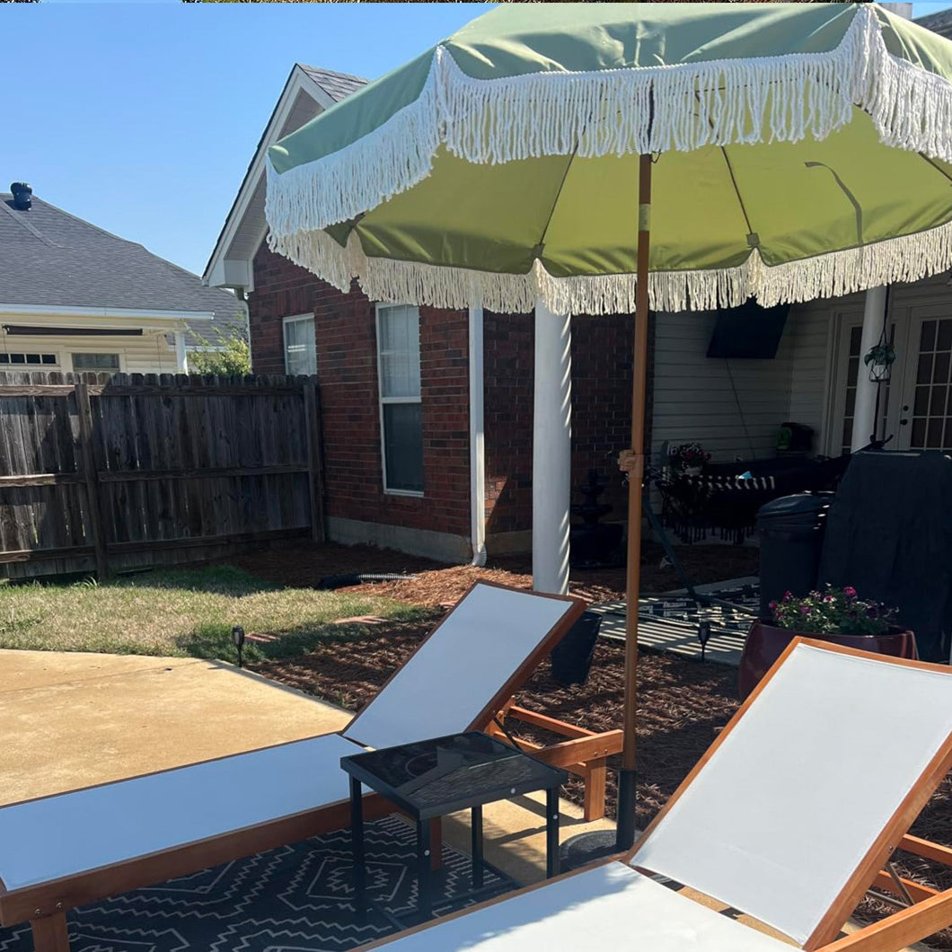 A lawn chair and an AMMSUN 7ft 
green fringe sunbrella outdoor umbrella positioned in a serene backyard setting