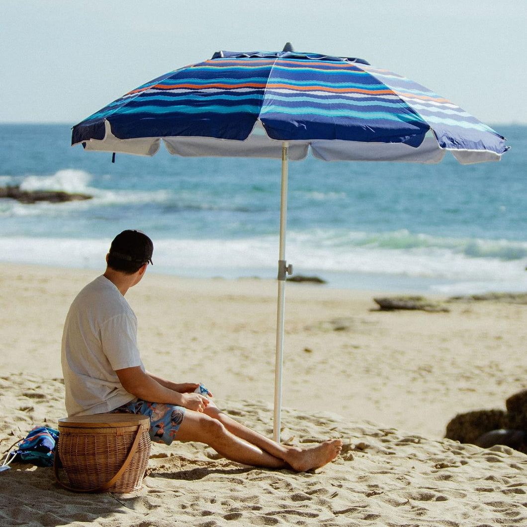 A man relaxes on the beach, seated under AMMSUN 7ft multicolor stripes travel beach umbrella with sand anchor