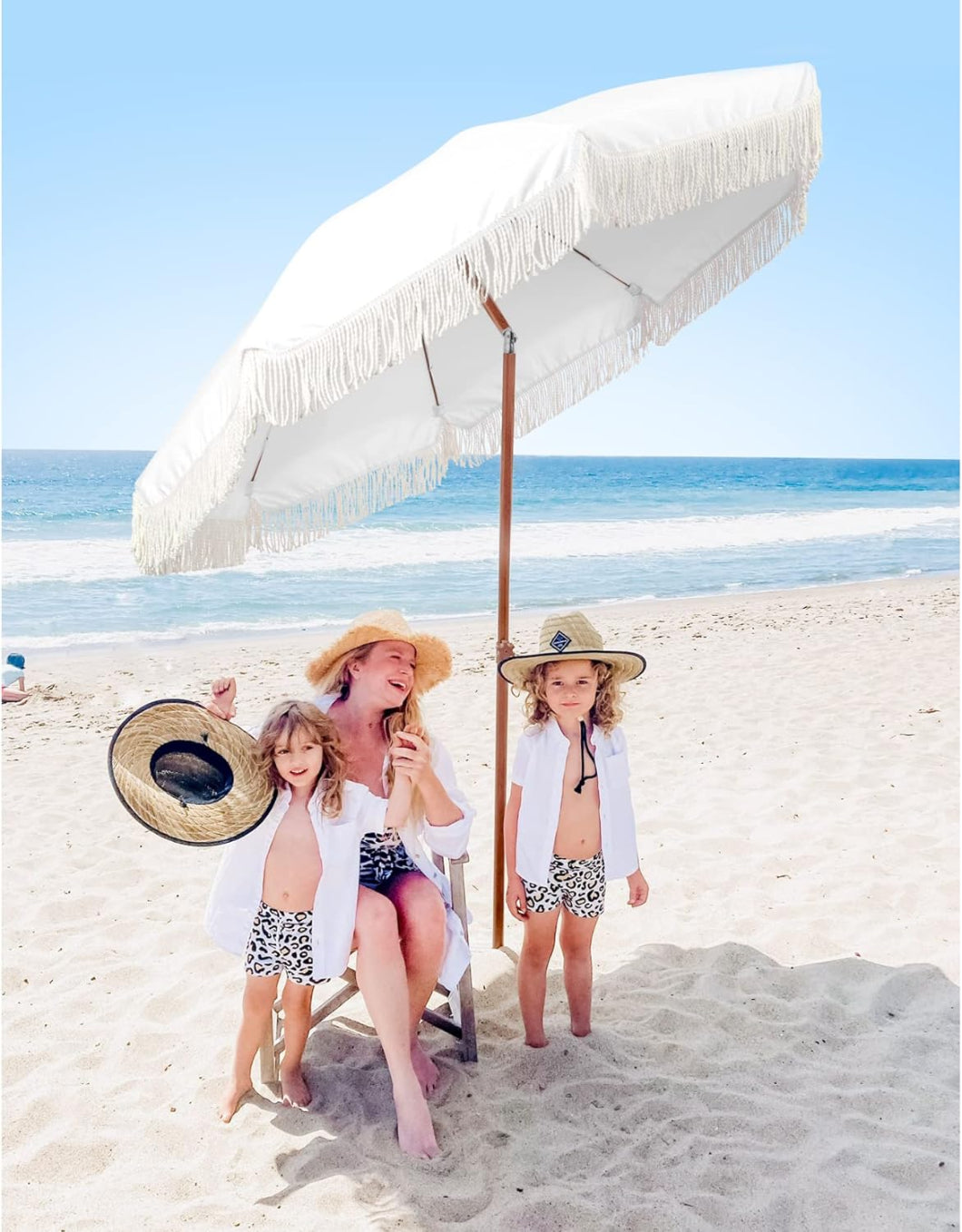 A woman and two children relax under AMMSUN 7ft elegant cream beach umbrella with fringe for plant umbrellas