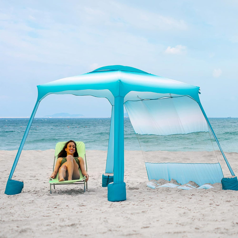 A woman relaxes beneath a AMMSUN 6.2'×6.2' beach cabana master canopy with portable Privacy sunwall, gradient blue