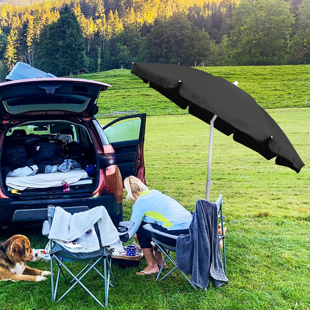 On the grass, a woman sits in a chair behind a car organizing things, with an AMMSUN 6ft umbrella outdoor patio