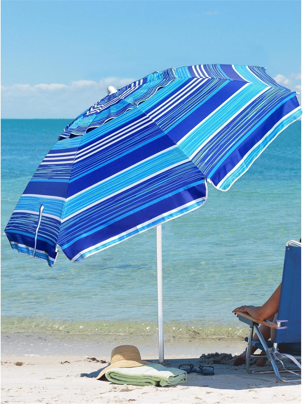 A person relaxes under an AMMSUN 6.5ft blue stripes umbrella outdoor patio on the beach