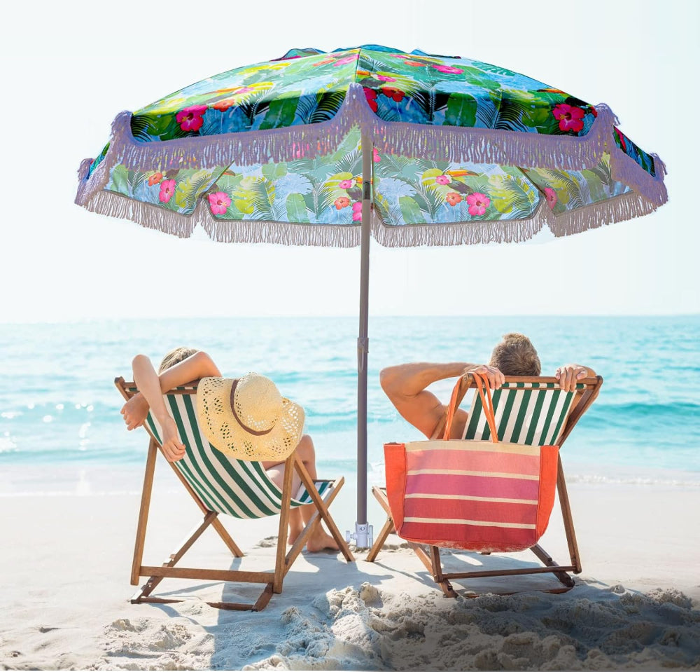 Two people enjoying the shade under an AMMSUN 6.5ft tropical patio umbrella with fringe for beach with sand anchor