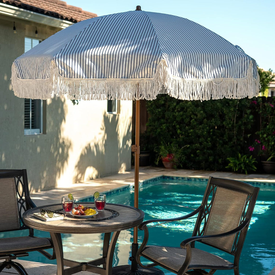 A white and blue striped fringe pool umbrellasis positioned on a patio table for table umbrellas