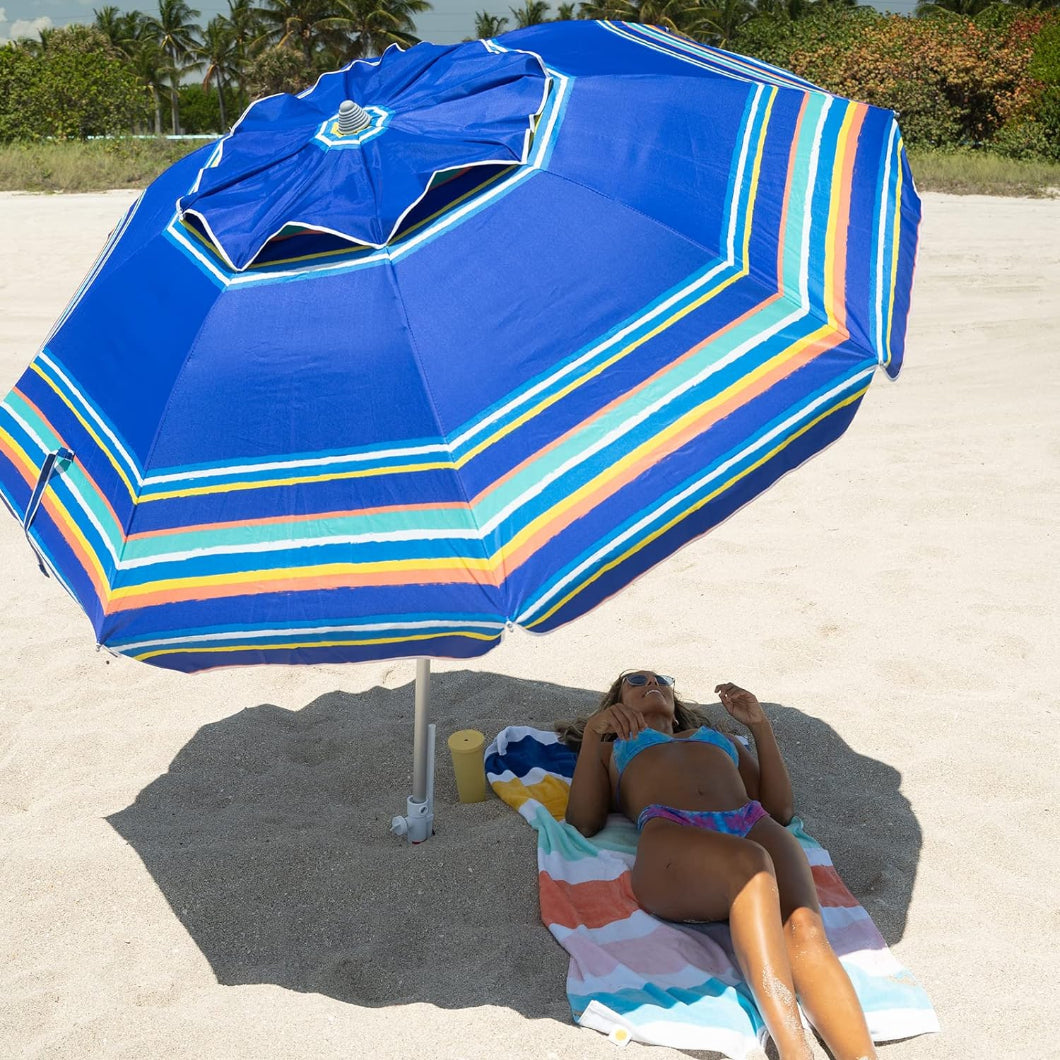 A woman is lying under AMMSUN 7ft blue strips travel beach umbrella with sand anchor for parasol