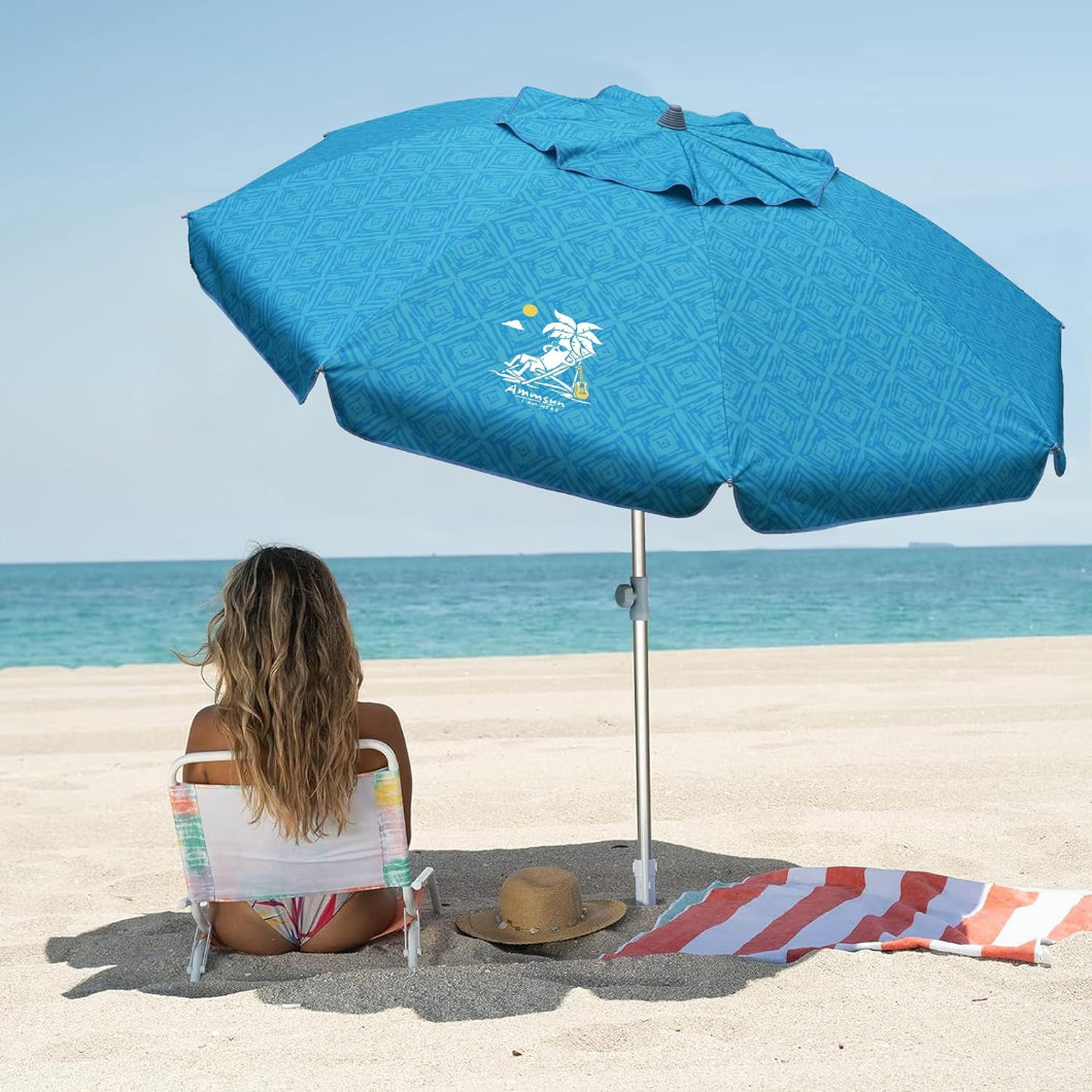 A woman relaxes on the beach, seated under AMMSUN 7ft Sky Whirlpool Teal beach umbrellas for sand with sand anchor