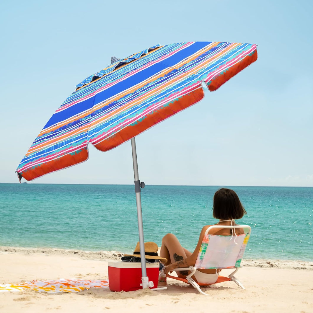 A woman sitting under AMMSUN 7ft caribbean twilight beach umbrellas heavy duty wind with sand anchor on beach