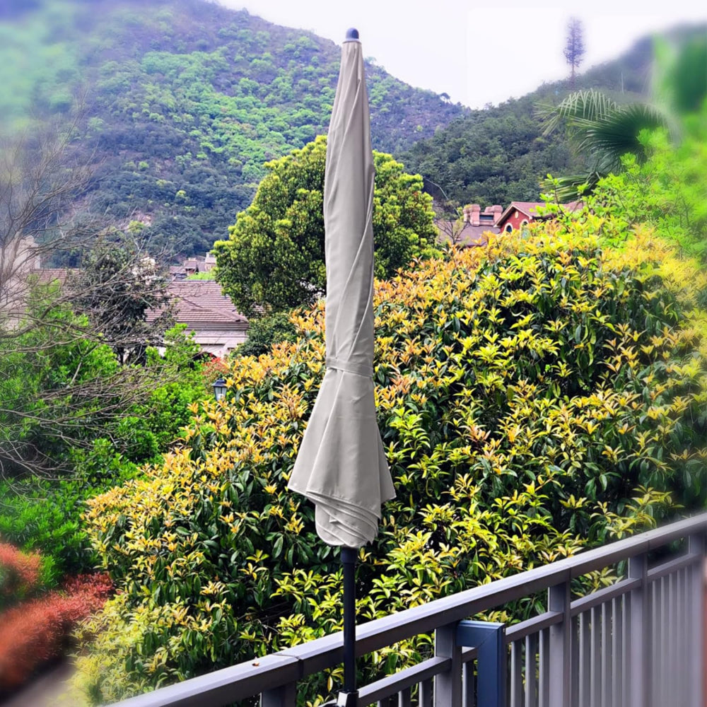 The lower pole of the AMMSUN 6.5ft beige outdoor umbrellas outside secured to a balcony railing.