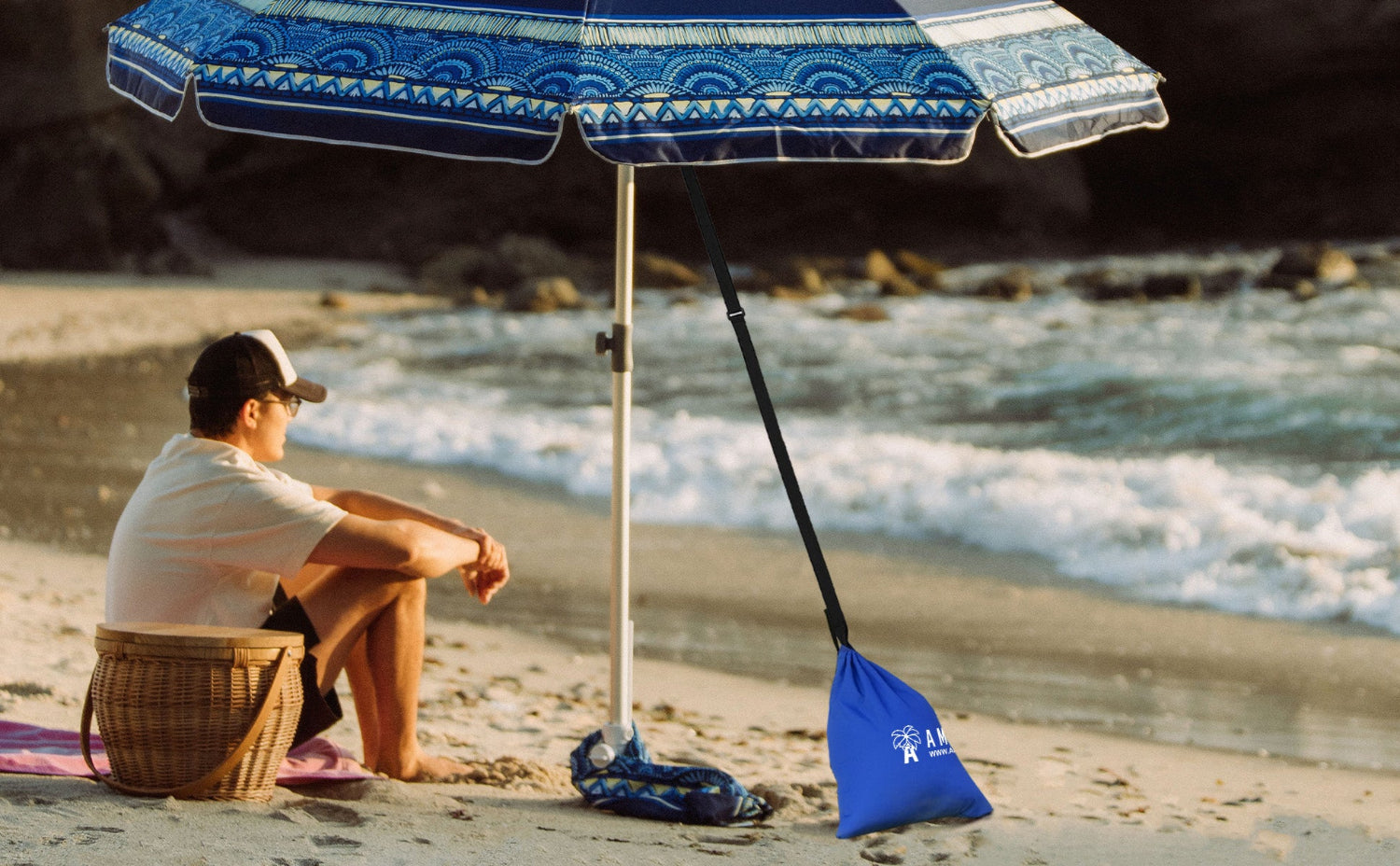 A man sitting under an umbrella secured on beach by AMMSUN beach umbrella additional sand bag