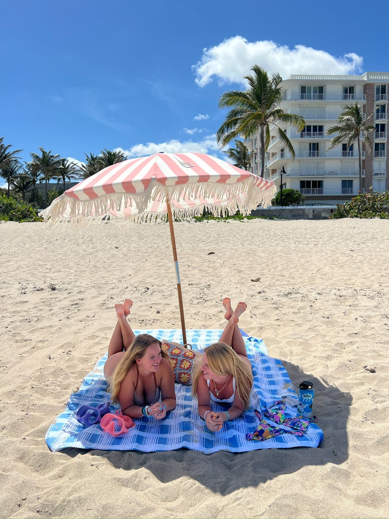 Two women lying on the blanket beneath AMMSUN 6.5ft pink outdoor umbrellas for patio with fringe on beach